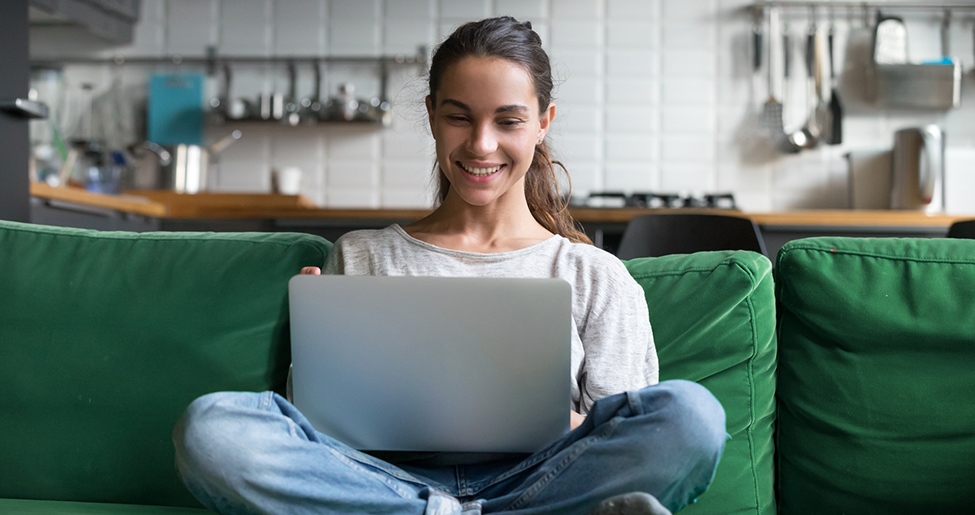 Woman sat on sofa with crossed legs and laptop on lap