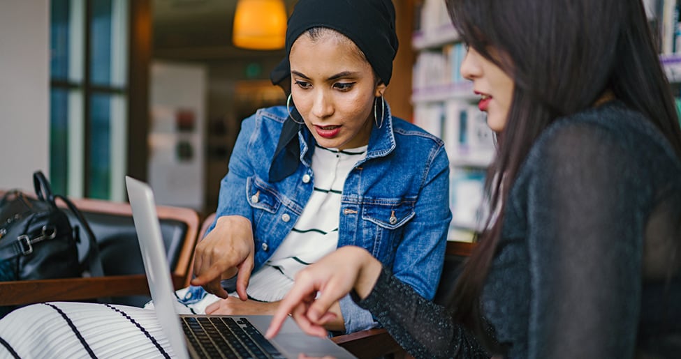 Two women pouring over a laptop screen