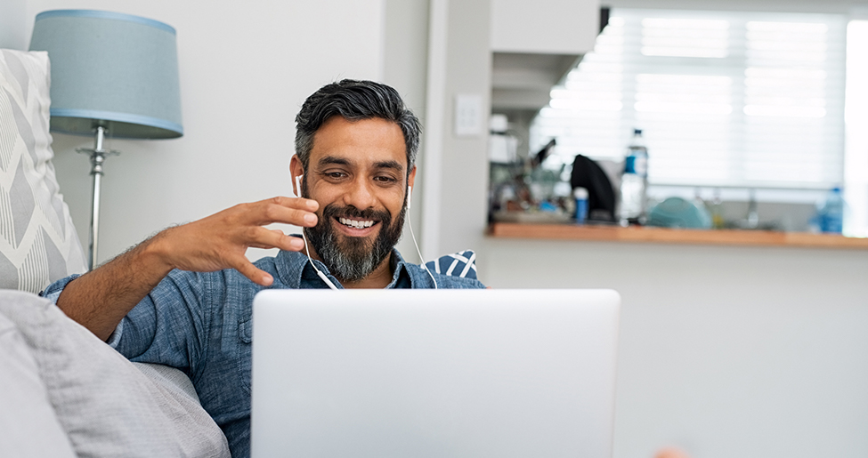 man gesticulating on video call sitting in front of laptop