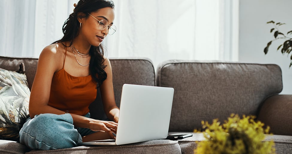 Woman sitting on sofa with laptop