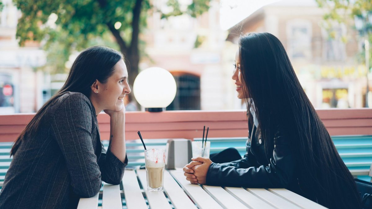 Two women talking over smoothies. Article for CharityJob.